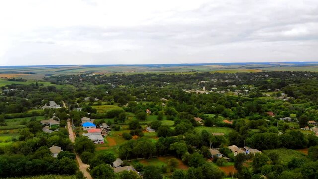 Aerial drone shot of Donduseni city with multiple residential buildings and greenery and fields in Moldova
