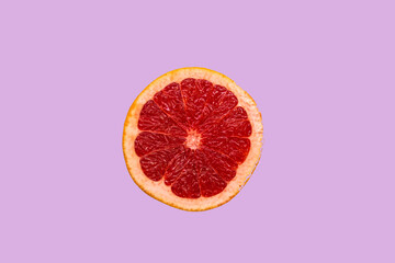 isolate of half a juicy grapefruit on a purple background