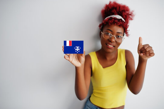 African woman with afro hair, wear yellow singlet and eyeglasses, hold French Southern Territories flag isolated on white background, show thumb up.