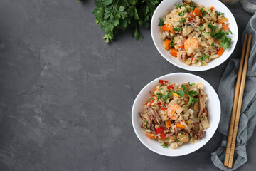 Two plates fried rice with seafood, vegetables, ginger and parsley on dark background. Asian cuisine. Vegetarian food. View from above. Copy space