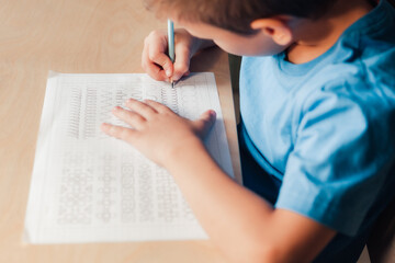 Side view to little boy doing writing exercises. Child writing with pencil. Children education concept