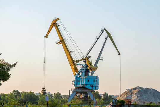 Harbour cranes are loading sand and gravel on a barge. Loading materials by crane