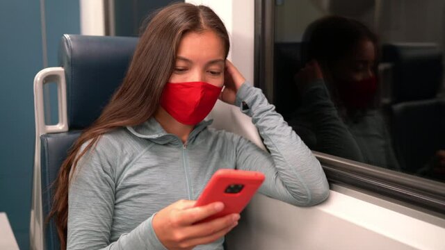 Face mask concept. Woman wearing mandatory mask in public transportation. Train transport commuter. Multiracial woman passenger using mobile smart phone with face covering on commute