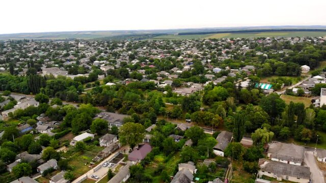 Aerial drone shot of Donduseni city with multiple residential buildings and greenery and fields in Moldova