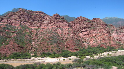 Foto de un valle por el que discurre un pequeño río, con montañas del período paleozoico a los lados.	
