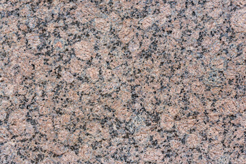 Granite texture. Natural pink granite with a grainy pattern. Stone background. Solid rough surface of rock. Durable construction and decoration material. Close-up.