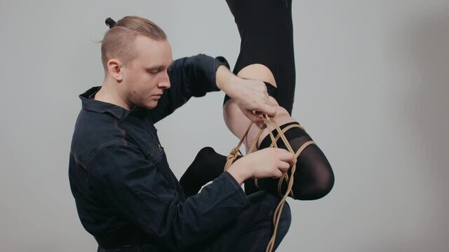 Shibari master shows how to tie the leg with ropes correctly. Rope bondage.