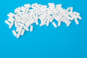 White pills on the blue paper background 