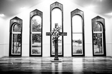 Wooden cross altar with floral arrangement in a small chapel with large windows