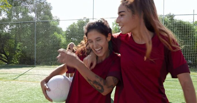 Two female soccer players hug and walk together after practice