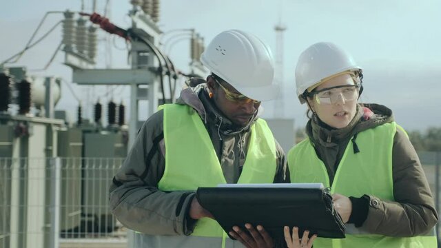 African-American power electrical substation worker and skilled construction engineer lady discuss project perspectives closeup
