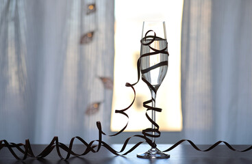 Glass of champagne decorated with decorative ribbon on the table. Christmas decoration.