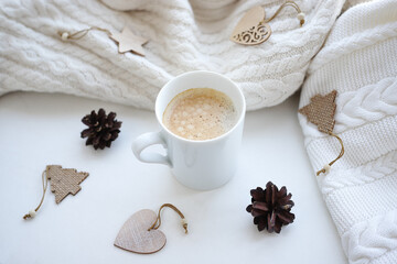 White cup with coffee decorated with pine cones and wooden Christmas decorations