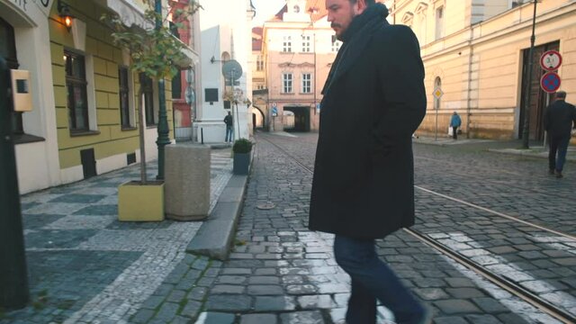 The man cross the street. A city dweller crosses the road according to traffic rules on a marked pedestrian zebra crossing. Tram tracks in the old city center.