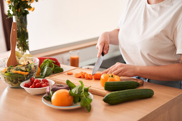 Woman chopping carrot with a knife