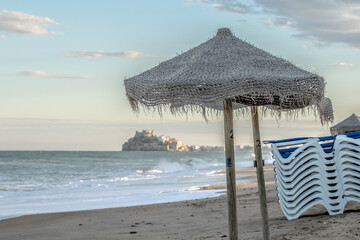 empty straw umbrellas in the sand in autumn on the beach