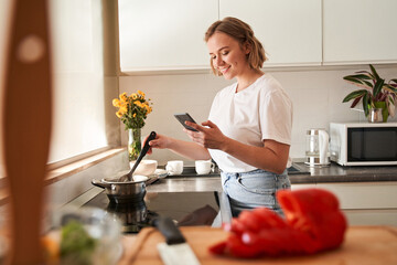 Woman stirring soup with fresh vegetables