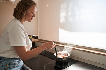 Woman stirring soup with fresh vegetables