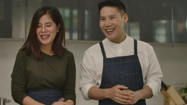 Loving Couple Cooking Together In Modern Kitchen Enjoy Talking And Prepare The Ingredients. Happy Family Husband And Wife Smiling In Kitchen. Married People, Lifestyle, Love, Leisure Activity Concept
