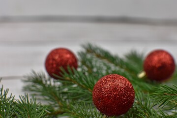 Christmas composition with red decoration and needls. Red christmas ball on spruce branch. Place for text 