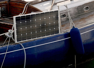 Un pannello solare montato su una barca a vela di legno con lo scafo blu. 