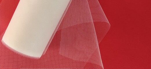 Fabric - white mesh in a roll on a red background. Nylon tape for tying bows on hair. A skein of...