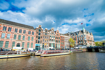 Fototapeta na wymiar AMSTERDAM, THE NETHERLANDS - APRIL 25, 2015: Traditional houses and buildings on the canal with boats on the water