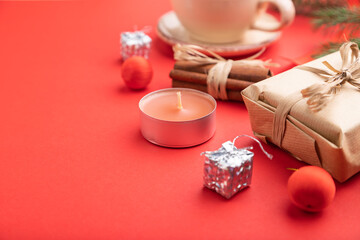Christmas or New Year composition. Decorations, box, fir and spruce branches, cup of coffee, on a red background. Side view, copy space, selective focus.