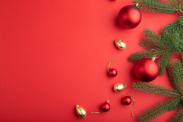 Christmas or New Year composition. Decorations, red balls, fir and spruce branches, on a red background. Top view, copy space.