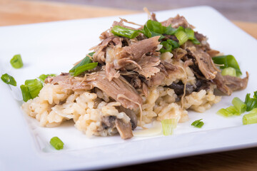 Gourmet mushroom risotto with duck meat on top.