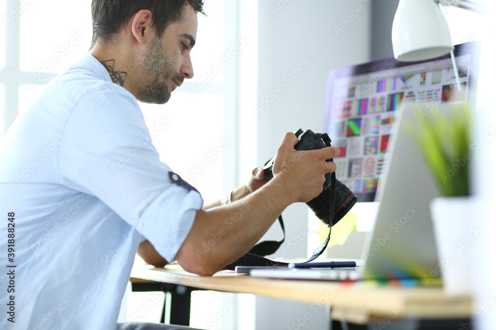 Poster portrait of young designer sitting at graphic studio in front of laptop and computer while working o