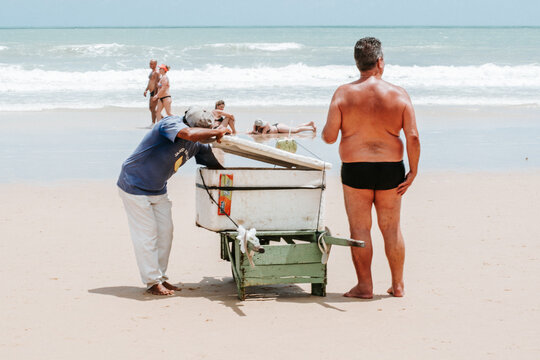 Isolated man on swimwear - casual pose- buying a coconout water from a local selling on the beach