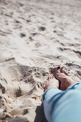 Woman tanned legs on sand beach. Travel concept.