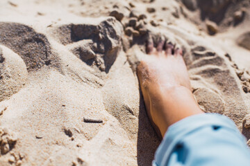 Woman tanned legs on sand beach. Travel concept.