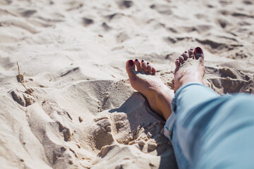 Woman tanned legs on sand beach. Travel concept.