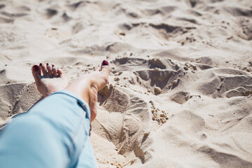 Woman tanned legs on sand beach. Travel concept.