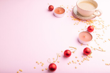 Christmas or New Year composition. Decorations, red balls, cup of coffee, on a pink background. Side view, copy space.