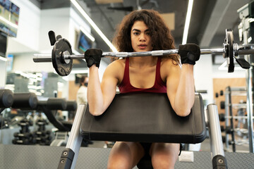 Fototapeta na wymiar Latin woman making eye contact and lifting weights