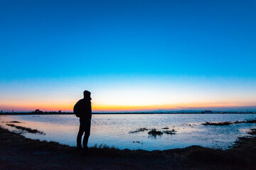 Fototapeta premium Joven observando el ocaso en la Albufera de València Young man watching the sunset in the Albufera de València 
