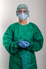 Enfermera protegida con traje (EPI), gafas y mascarilla, mira hacia el frente con las dos manos juntas