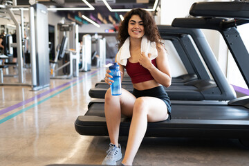 Fototapeta na wymiar Young hispanic woman sitting on a treadmill