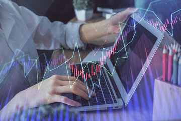 Double exposure of woman hands typing on computer and forex chart hologram drawing. Stock market invest concept.