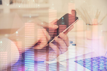 Double exposure of man's hands holding and using a digital device and forex graph drawing. Financial market concept.