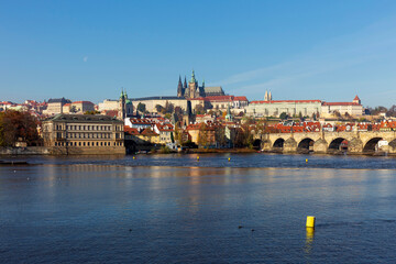 Obraz premium Autumn colorful Prague Lesser Town with gothic Castle and Charles Bridge above River Vltava in the sunny Day, Czech Republic