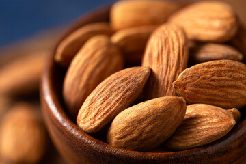 Close-up of whole raw almonds in a brown bowl