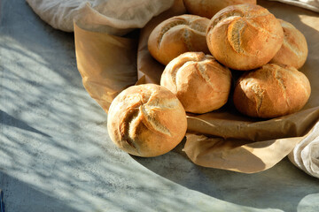 Kaiser, or Vienna buns in bread basket on on dark grey background with yellow Autumn leaves.