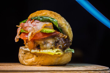 Hamburguesa slider clasica con fondo negro, lechuga,tomate y aguacate en pan artesanal 