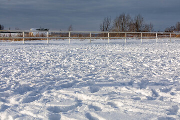 Rural winter landscape. A deep layer of snow with dents from the tracks. Blue sky in the background.