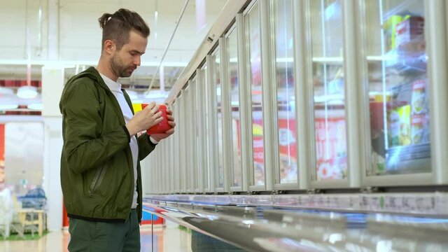 male shopper in grocery, choosing frozen food in supermarket