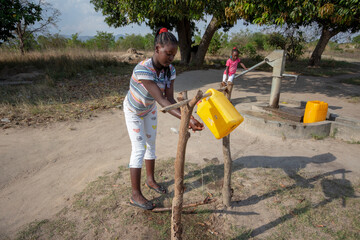 Young girl washing hands on gallon of water recycled and adapted on tree logs as hand washing...